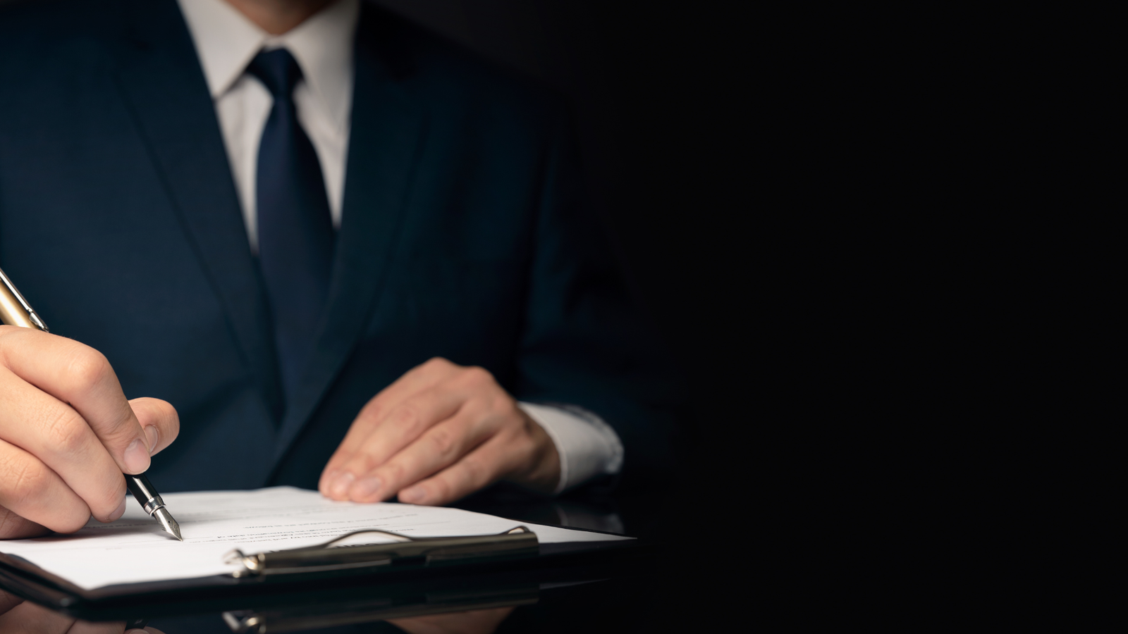 Imagem de um homem de terno e gravata trabalhando na mesa de um escritório